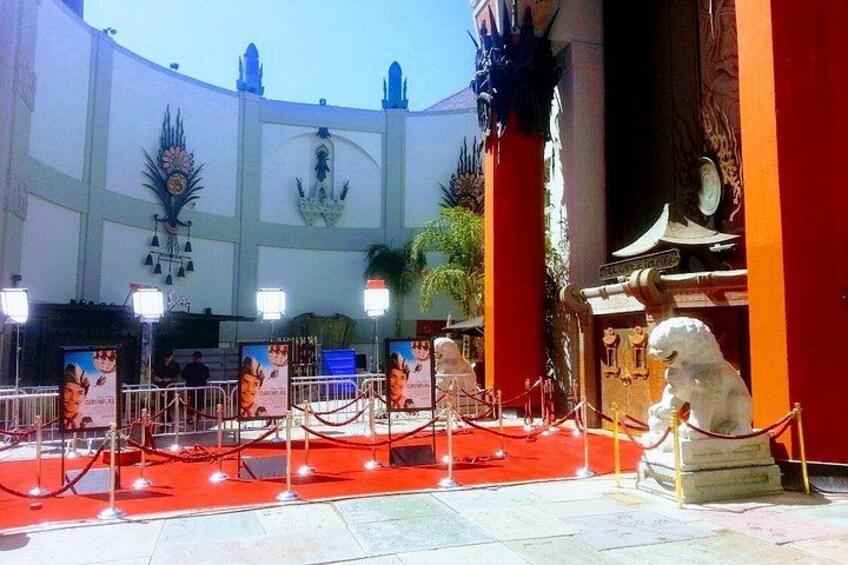 A red carpet event with a statue of a lion, a white building with decorative elements, and a red-roofed structure. 2