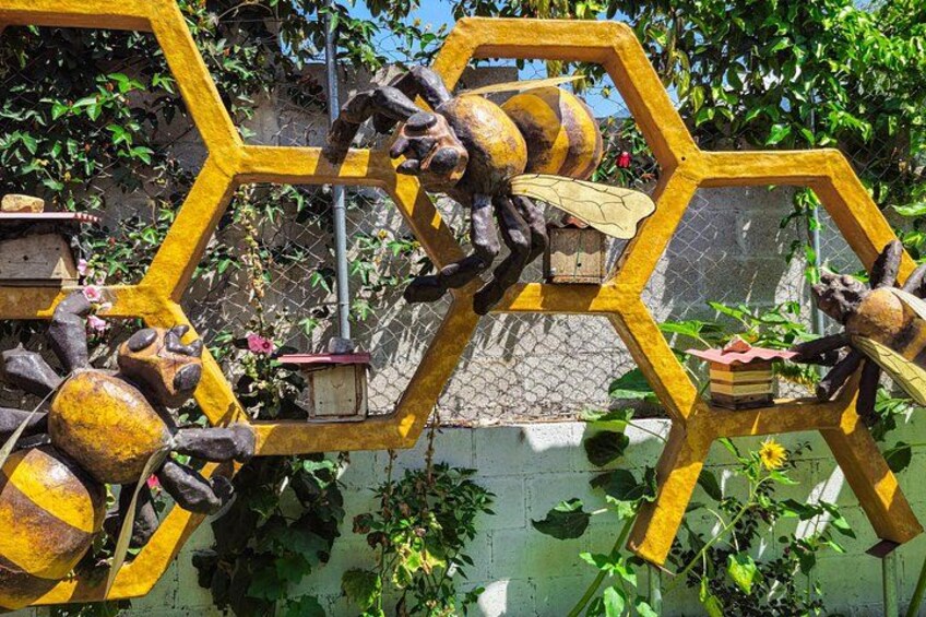 Een gele, zeshoekige constructie met mechanische onderdelen en een klein vogelhuis. 4