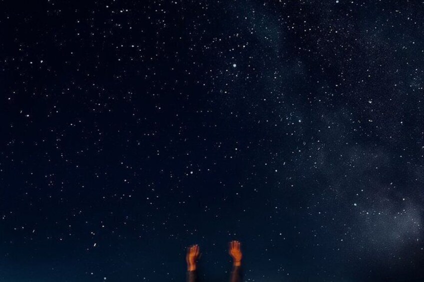 Cielo nocturno lleno de estrellas y una mano humana extendiéndose hacia arriba. 5