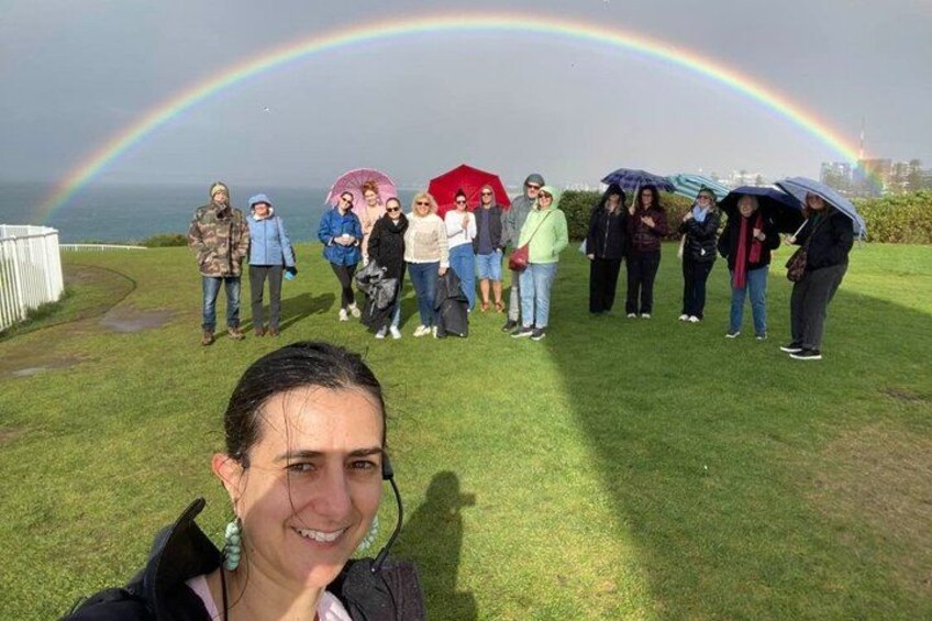 A group of people standing on grass with a rainbow in the background. 3