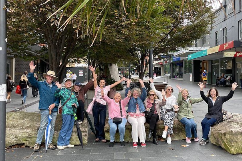 A group of people posing for a photo in an urban setting with trees and buildings in the background. 1