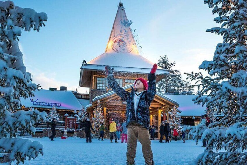 Eine Person mit karierter Jacke und roter Mütze steht in verschneiter Landschaft, im Hintergrund ein Gebäude. 5