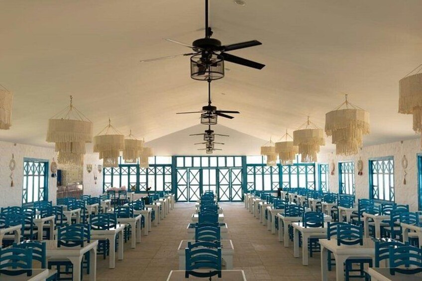 Une grande salle avec des rangées de chaises, un ventilateur de plafond et des luminaires suspendus. 4