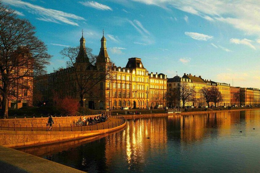 Ein Fluss mit in den Spiegelungen der Gebäude, einer Brücke und Bäumen am Ufer. 2