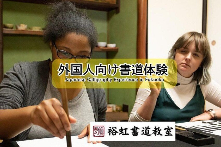 A person practicing calligraphy with a brush on paper, with calligraphy tools and a book on the table. 3