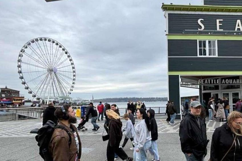 Een drukke waterkant met een groot reuzenrad en het gebouw van het Seattle Aquarium. 4