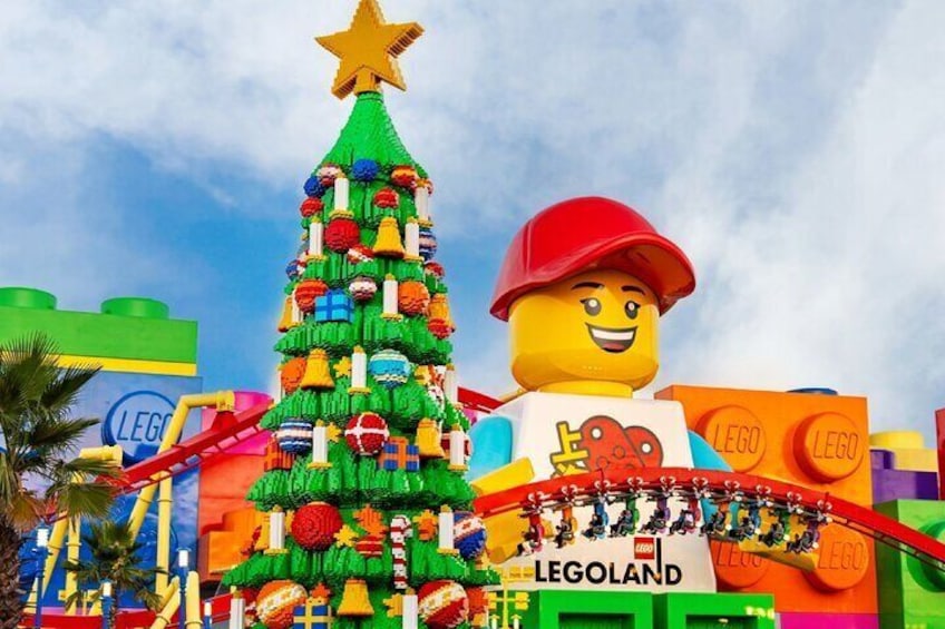 Un árbol de Navidad LEGO y una figura LEGO frente a un edificio con temática LEGO. 1