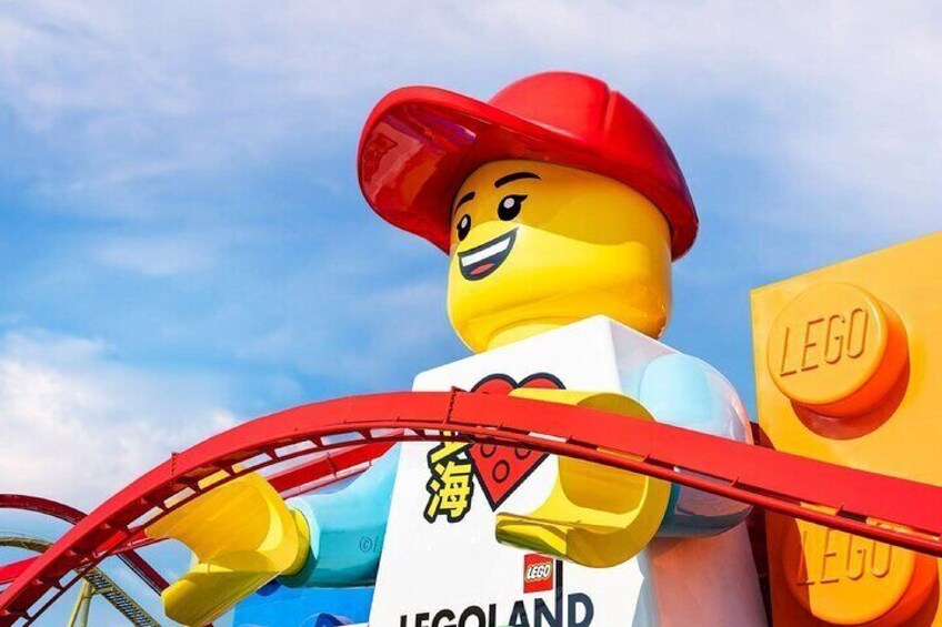 Una escultura de LEGO de un personaje con sombrero rojo y camisa azul, montando en una montaña rusa roja. 5