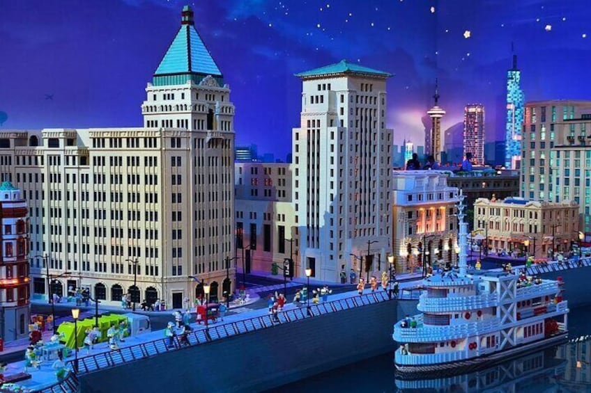 Un paisaje urbano nocturno con edificios iluminados, un río y un barco. 3