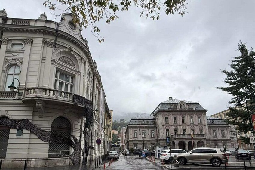 A historic building with ornate architecture, a wet street, and parked cars. 5