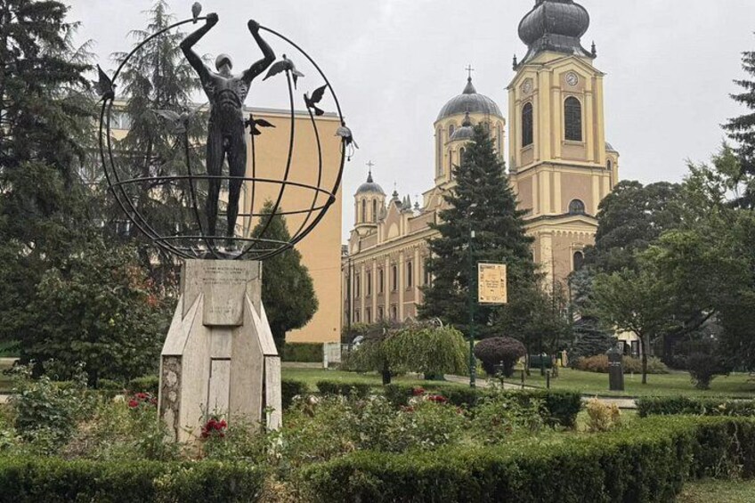 A statue of a man holding a globe, a church with domes, and manicured gardens. 4