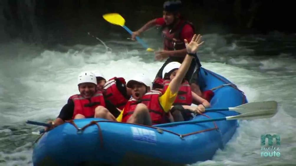 A group of people in a blue raft navigating a river. 5