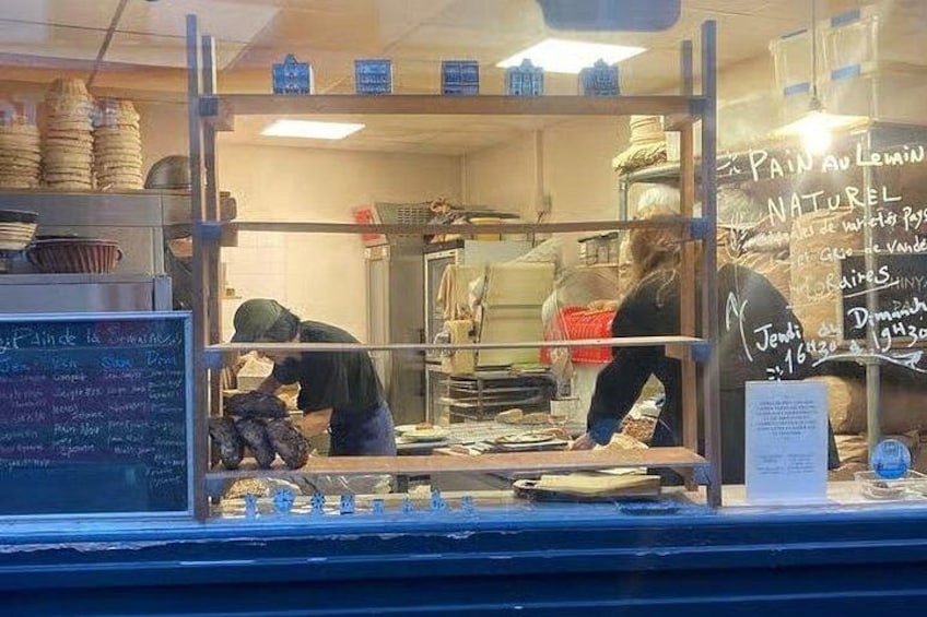 Une boulangerie avec un tableau noir servant de menu et une personne qui prépare des aliments. 4