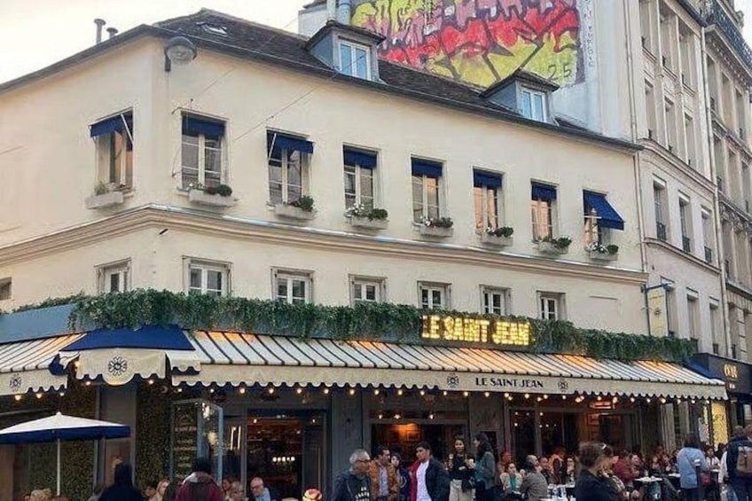 Un bâtiment sur lequel on peut lire l’inscription « LE SAINT JEAN », et une foule de personnes se trouve à l’extérieur. 2
