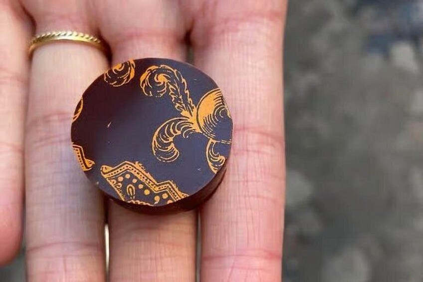 Een hand die een cirkelvormig voorwerp vasthoudt, met een zwarte achtergrond en gouden decoraties. 3