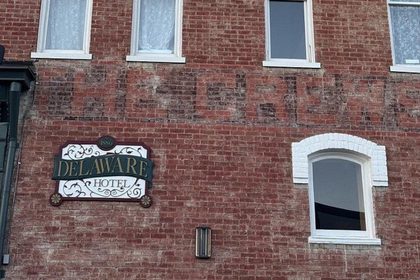 A brick building with a sign that reads 'Delaware Hotel' and a window with a white frame. 2