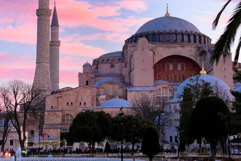 A large mosque with a prominent dome and minarets, surrounded by trees and a clear sky. 5