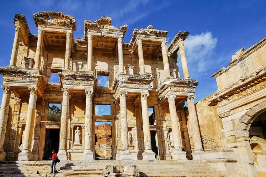 Ancient ruins with columns and arches, a person standing in front, and a clear blue sky. 3