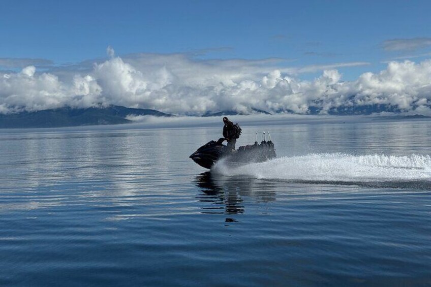 Una persona che fa jet ski su acque calme, con montagne sullo sfondo. 3