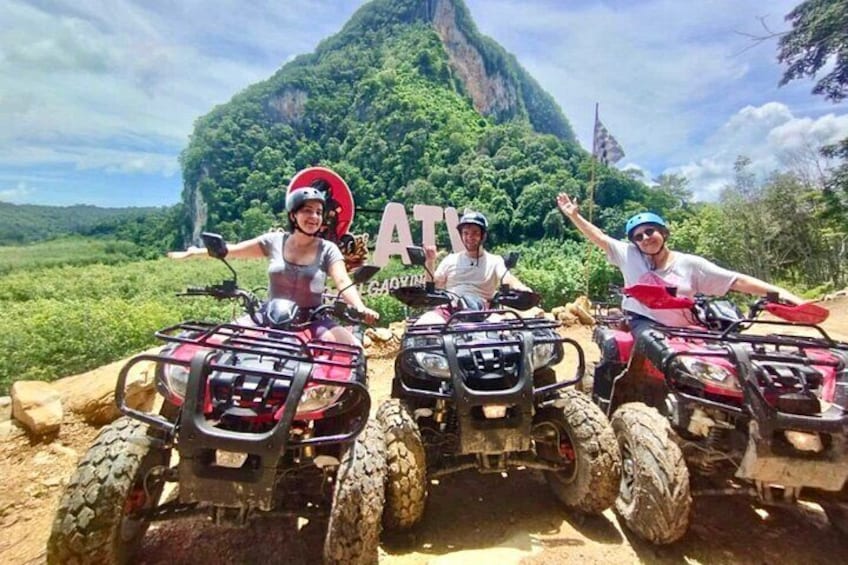 Three people on ATVs with a mountainous landscape in the background. 3