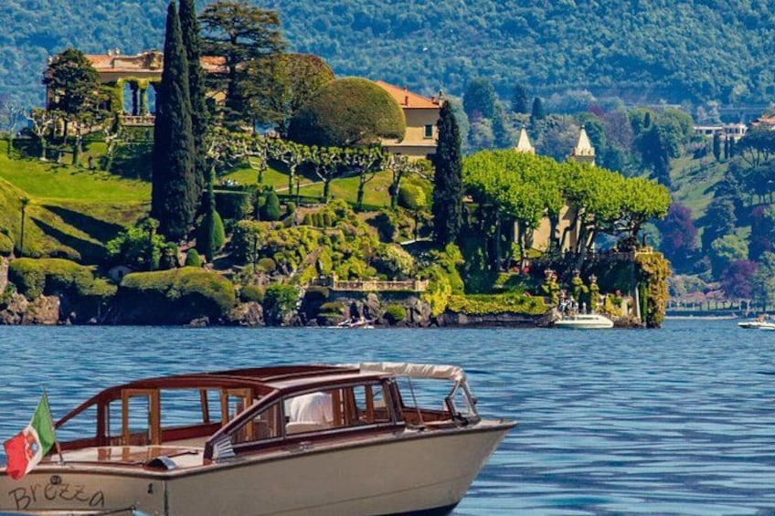 A boat on calm water, a green landscaped island with a building, and a clear sky. 2