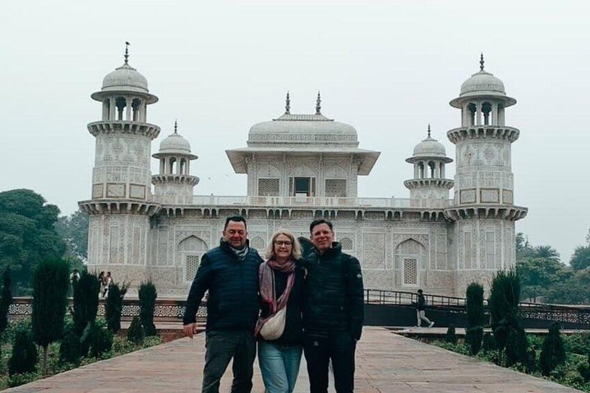 A large white marble building with domes and minarets, surrounded by greenery. 2