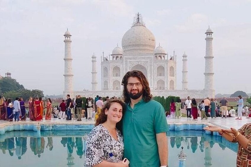A person standing in front of the Taj Mahal with a reflection in the water. 3