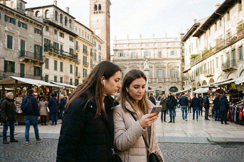 Two people standing in a crowded square with historic buildings and a tower in the background. 5