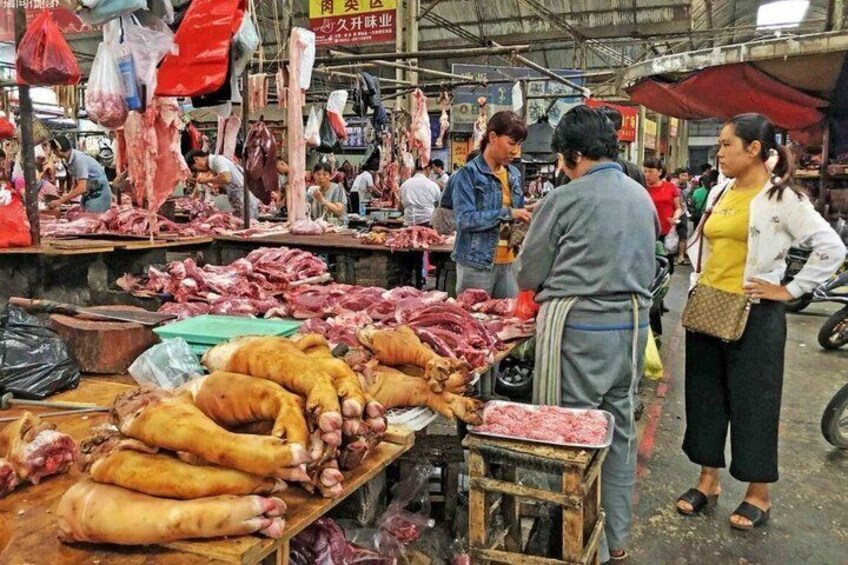 Ein belebter Markt mit verschiedenen Fleischsorten, die auf Tischen präsentiert werden. 1