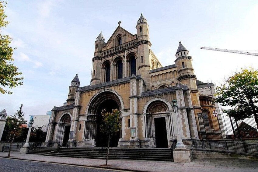 A historic cathedral with large arches, a prominent bell tower, and a staircase leading to the entrance. 5