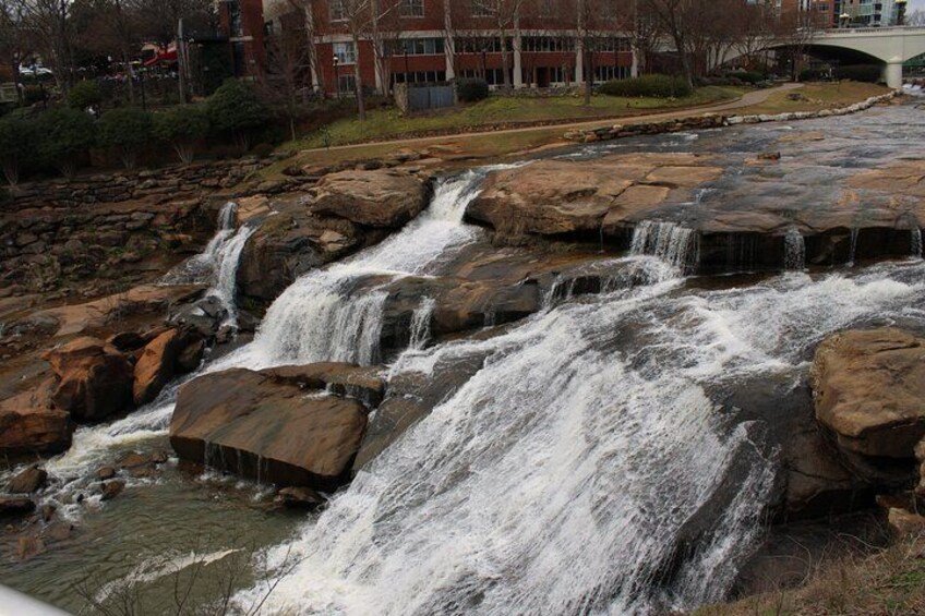 A multi-tiered waterfall cascading over large rocks in a park setting. 1
