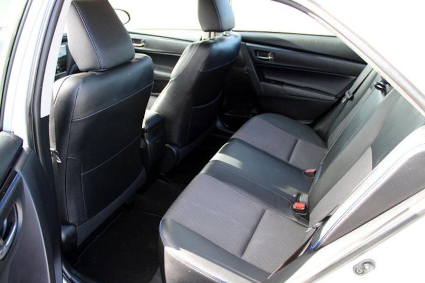 A car's interior with black leather seats and a grey center console. 3