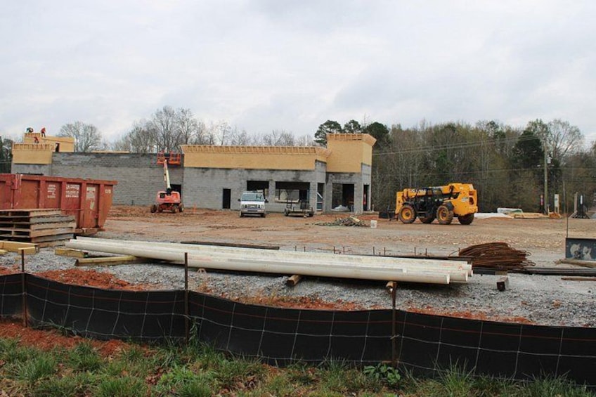 A construction site with a yellow excavator, a white truck, and a building under construction. 5