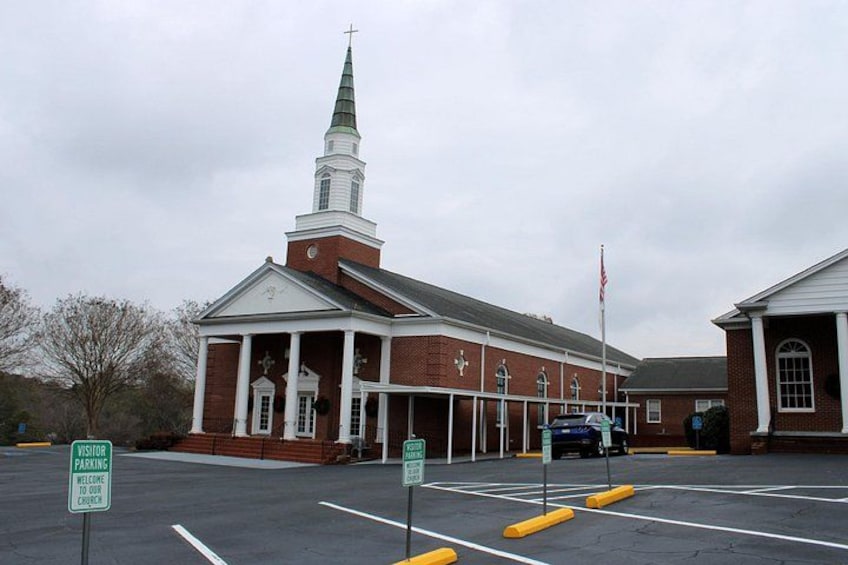 A church with a steeple, a parking lot, and a visitor parking sign. 4