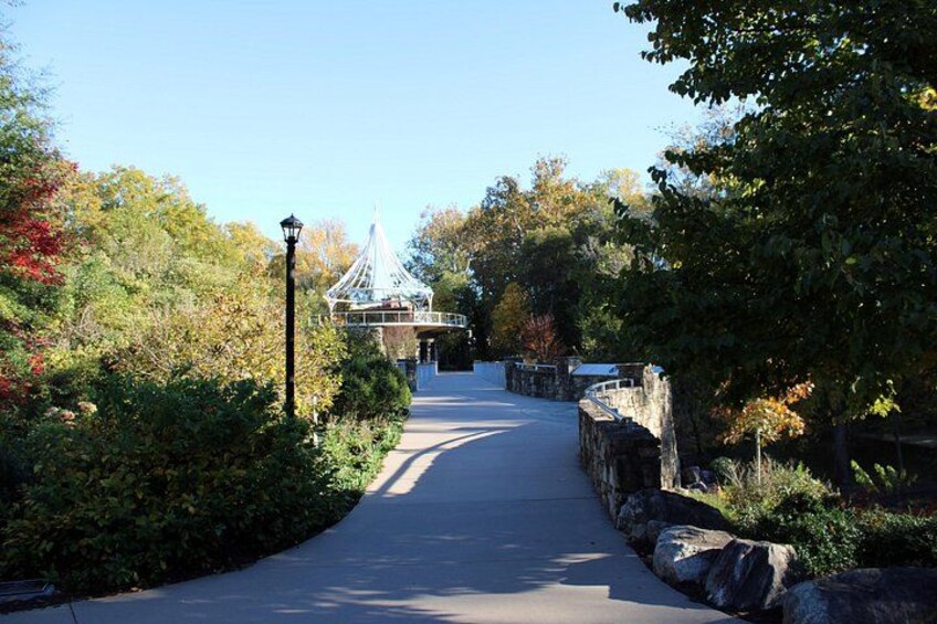 A paved pathway flanked by stone walls and lush greenery, leading to a gazebo-like structure. 3