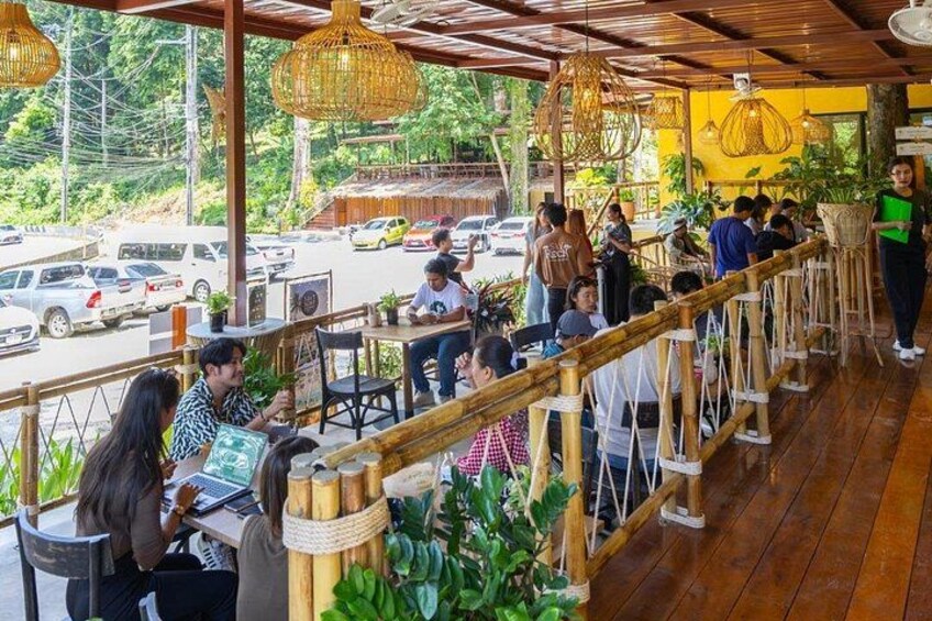 Een restaurant met terras, houten leuningen en hangende rieten lampen. 4