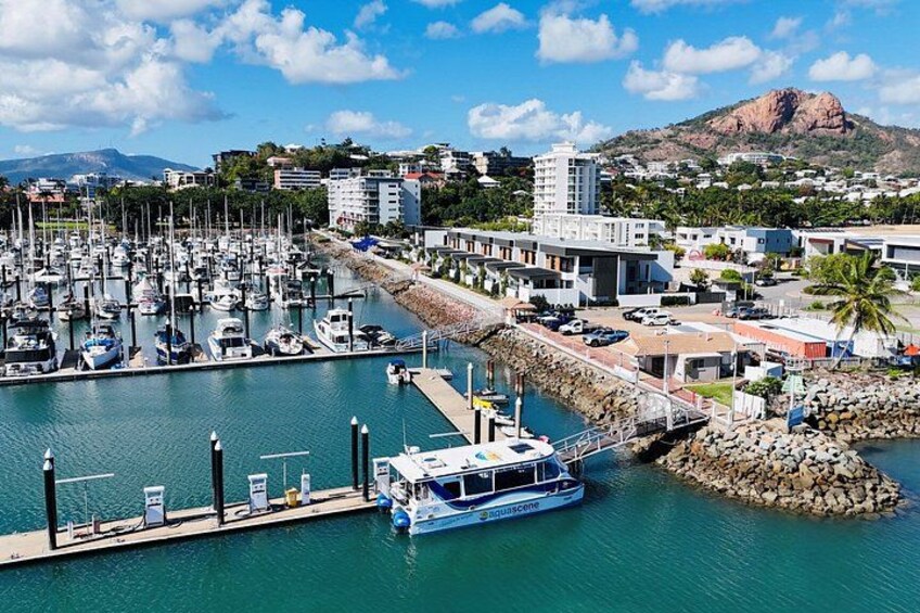 A marina with boats docked, a pier, and a mountain in the background. 1