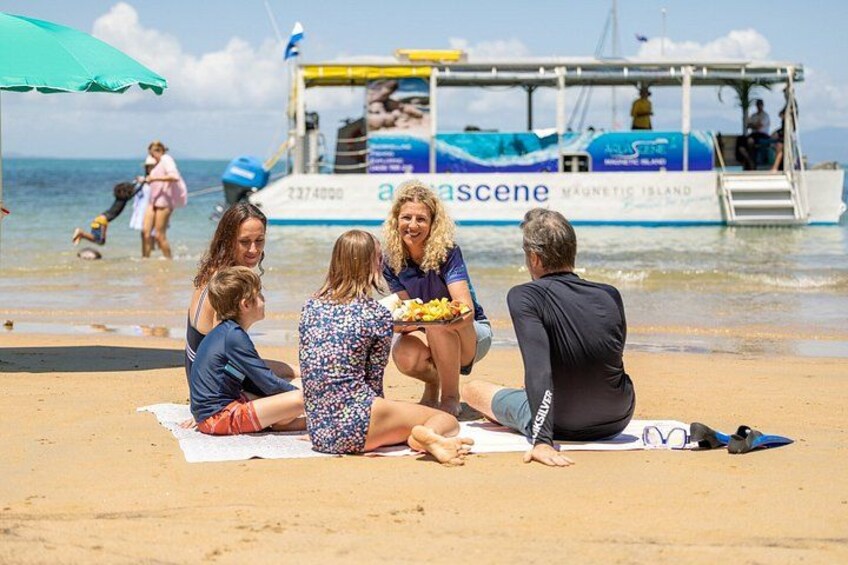 A group of people sitting on a beach with a boat in the background. 5