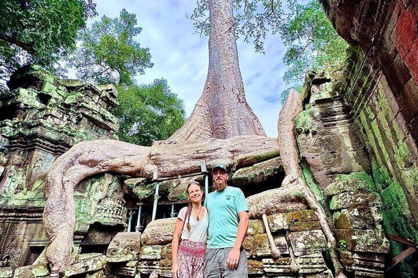 A man and woman standing in front of a large tree-like structure with carvings. 5