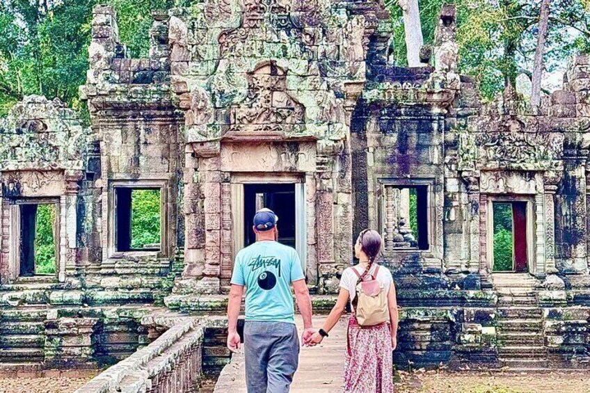 A man and a woman walking towards a temple with intricate carvings and multiple doorways. 4
