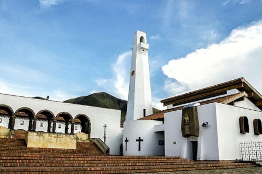 A church with a tall bell tower, arched windows, and a cross on the facade. 4