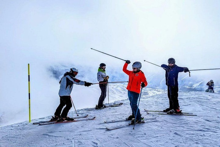 Skiers on a snowy slope with poles, wearing helmets and jackets. 1