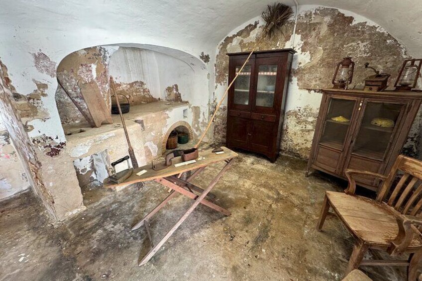Een oude, vervallen kamer met afbladderende muren, een houten kast en een open haard. 4
