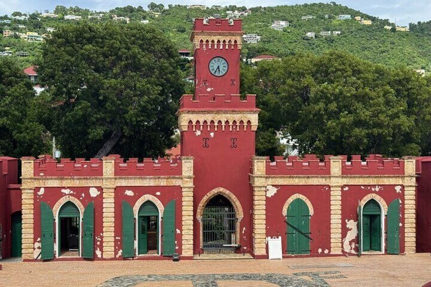 Een rood gebouw met een klokkentoren en groene deuren. 1