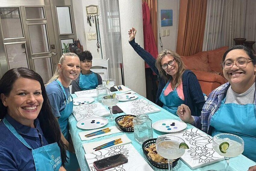 A group of people sitting around a table with drawing materials and plates of food. 2