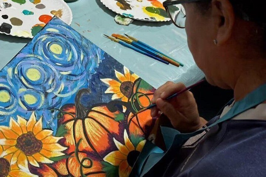 A person painting a canvas with sunflowers and pumpkins. 5
