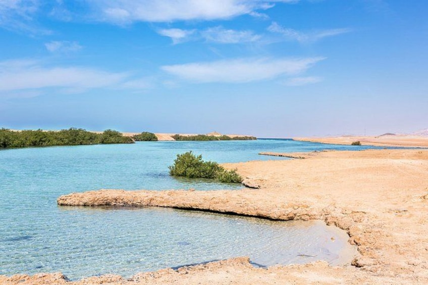 Un lago azul y transparente con orillas arenosas y vegetación escasa. 2