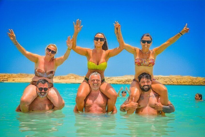 A group of people in a body of water with clear skies and a distant shoreline. 5