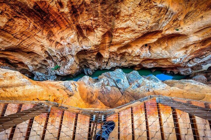 Une grotte avec des escaliers en bois et une piscine bleue au fond. 5