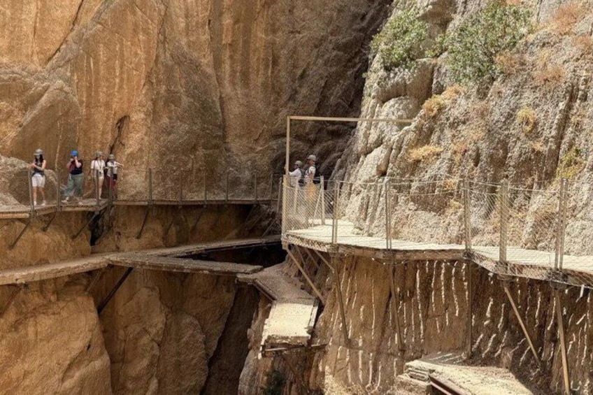 A metal bridge over a canyon with people standing on it. 2